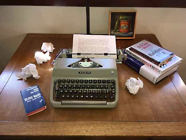 A Facity Typewriter with wads of cumpled paper and some reference books
